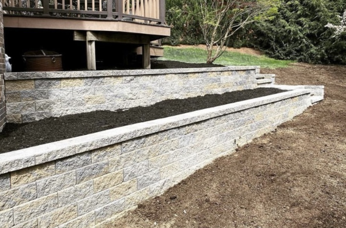 Tiered Breezewood retaining wall installation with planting beds beneath a deck in Paramus, Bergen County, NJ, by Masonry Pro Construction.