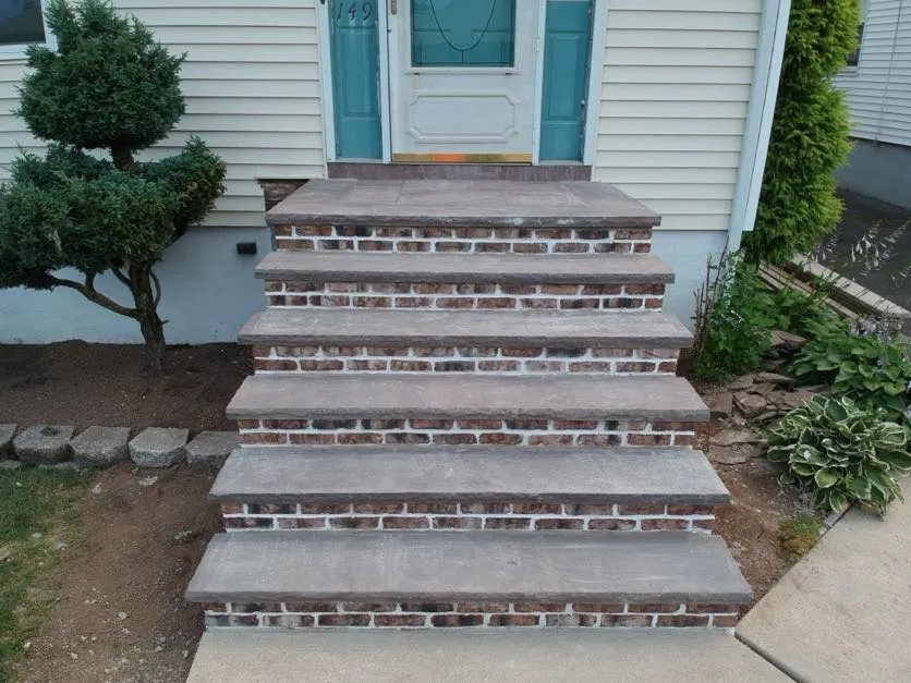 Newly constructed brick masonry steps from Masonry Pro Construction leading to a beige house in Totowa, Passaic County, NJ.