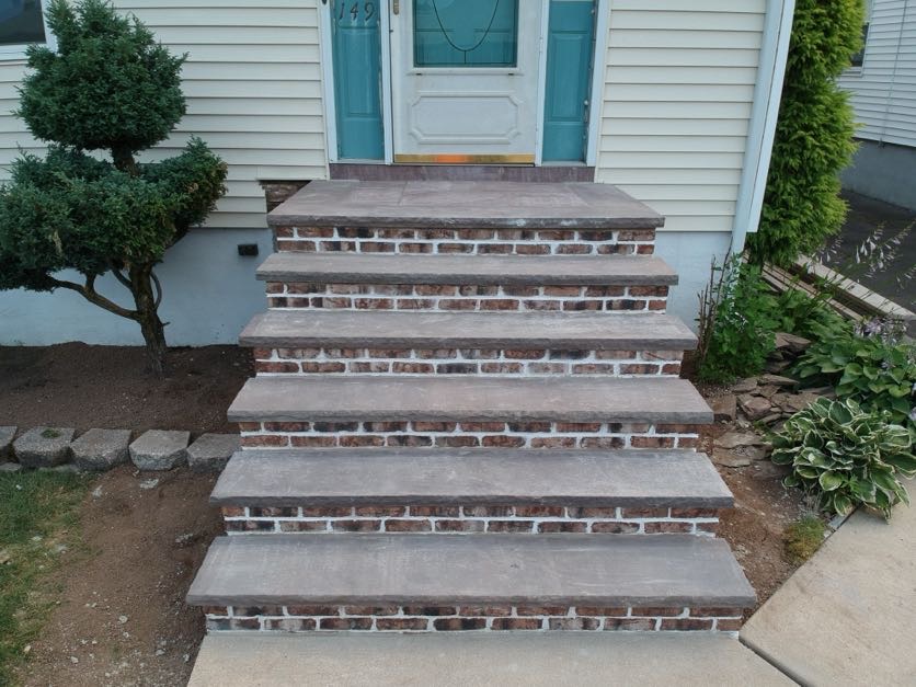 Newly constructed brick masonry steps from Masonry Pro Construction leading to a beige house in Totowa, Passaic County, NJ.