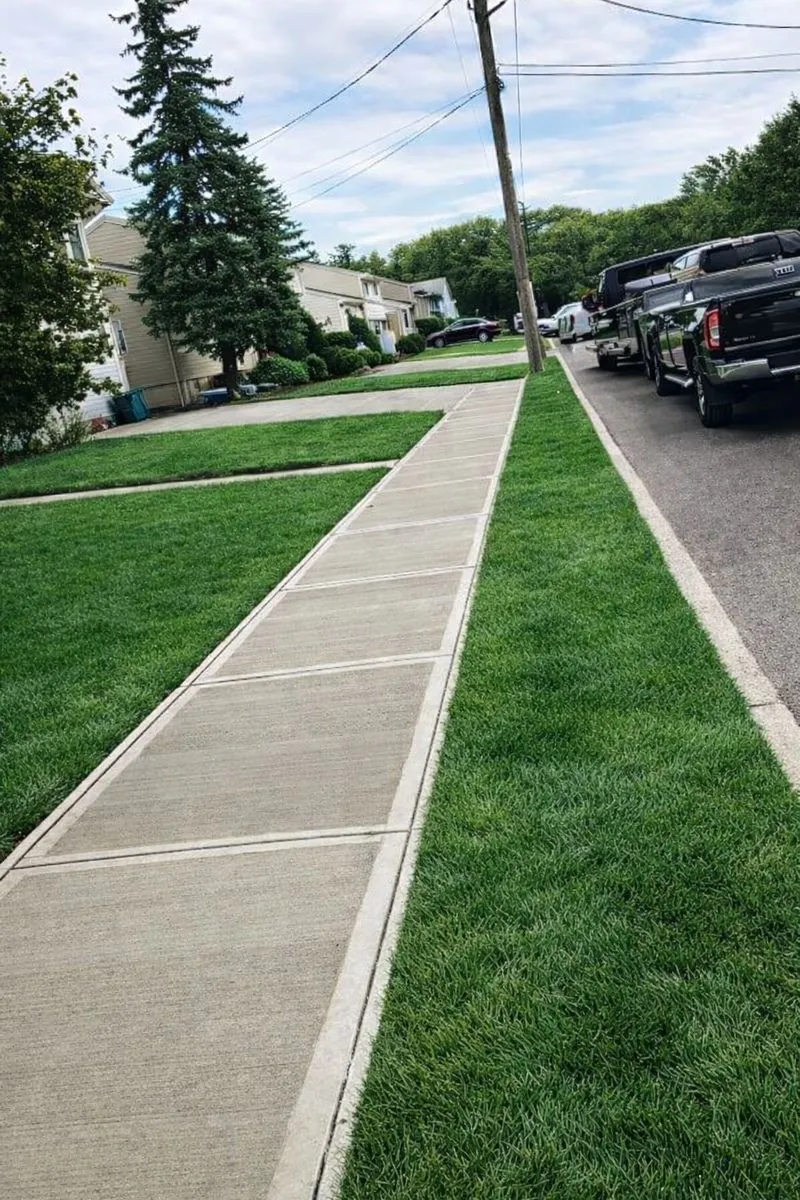 Newly installed concrete sidewalk and lush green lawn in Totowa, Passaic County, New Jersey.