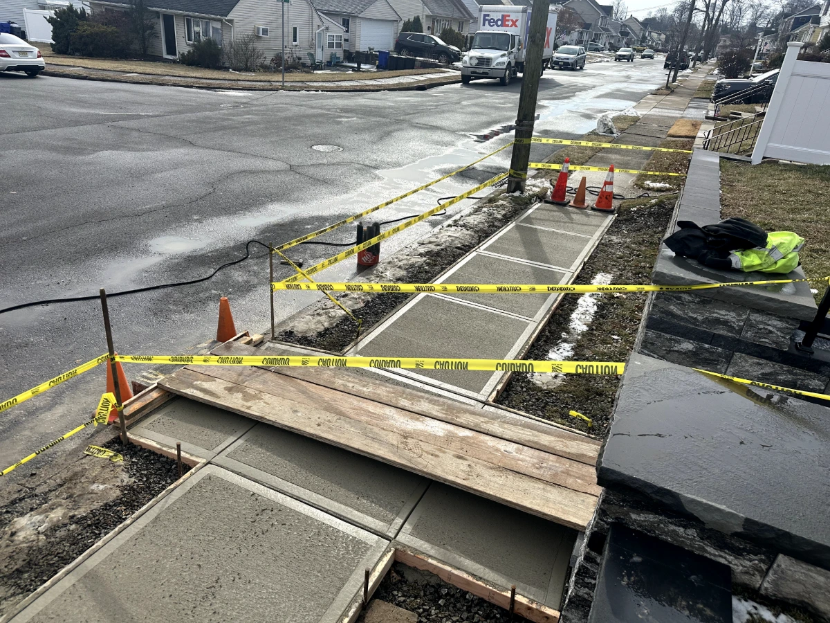 Concrete sidewalk slabs curing in winter conditions with control joints cut and forms still set in Totowa, NJ