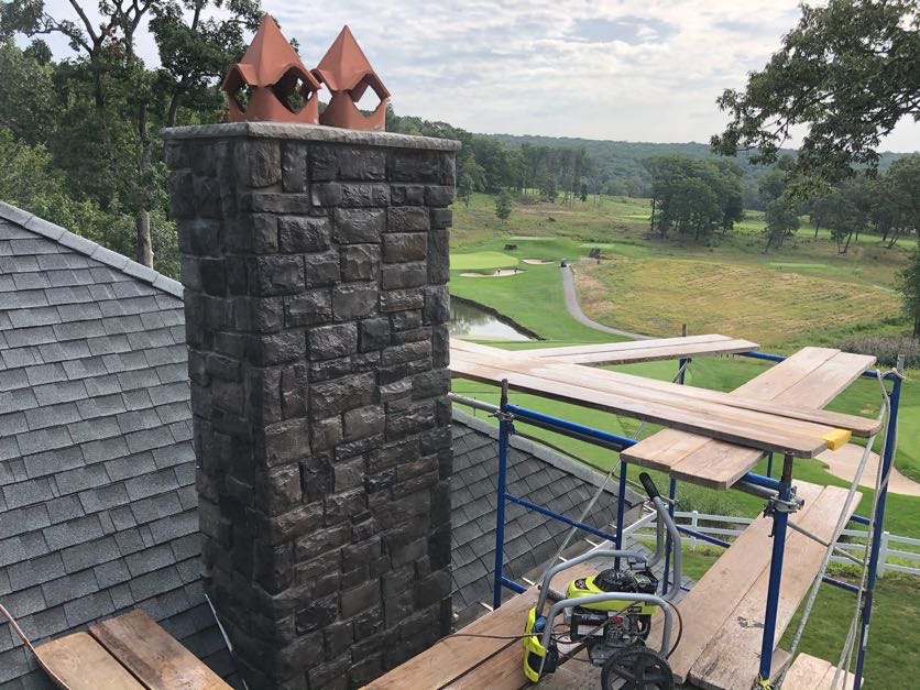 Stone masonry chimney and roof on a house in Wayne, Passaic County, NJ, with a golf course in the background, Masonry Pro