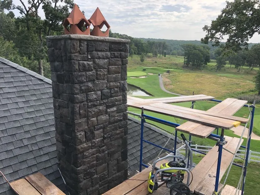 Stone masonry chimney and roof on a house in Wayne, Passaic County, NJ, with a golf course in the background, Masonry Pro