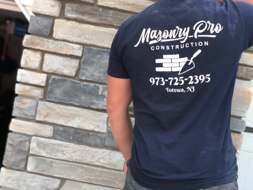 Masonry Pro Construction worker in front of a completed stone veneer installation at a home in Wayne, Passaic County, NJ.
