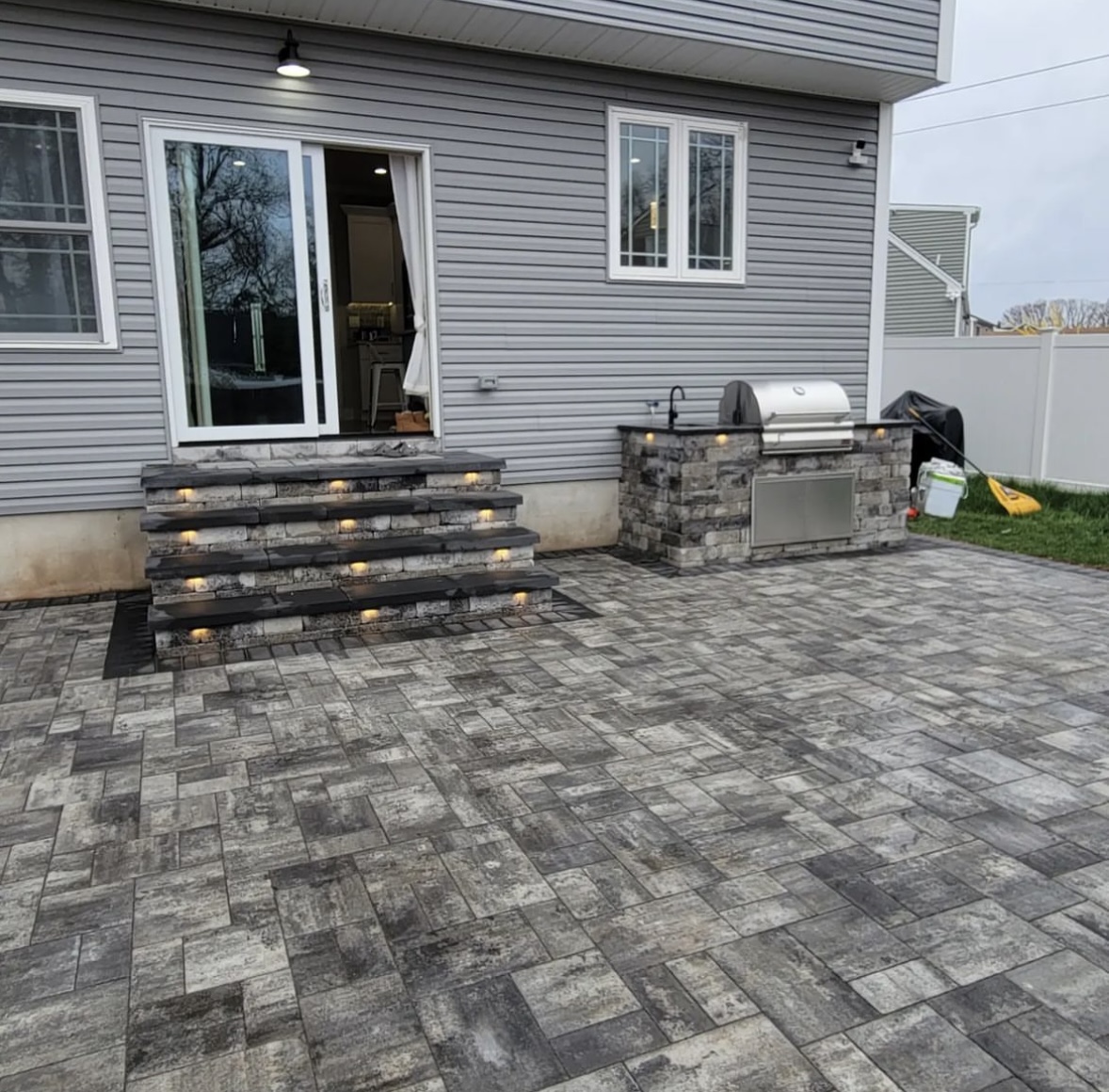 Paver patio with outdoor kitchen, stone steps with LED lighting at a home in Paramus, Bergen County, NJ, by Masonry Pro Construction.