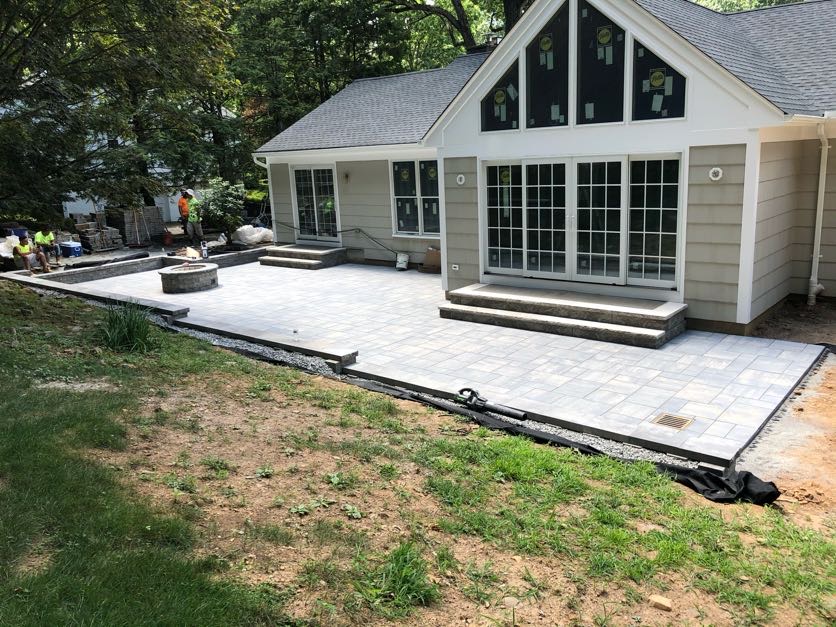 Large paver patio with fire pit and stone steps installation at a home in Essex Fells, Essex County, NJ, by Masonry Pro Construction.