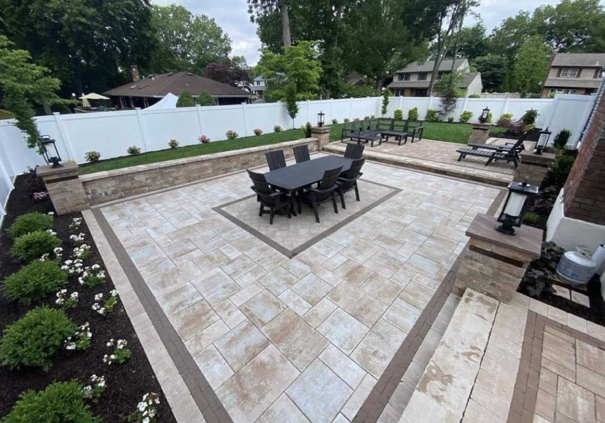 Large luxury paver patio with outdoor dining, seating areas, and stone pillars at a home in Paramus, Bergen County, NJ, by Masonry Pro Construction.