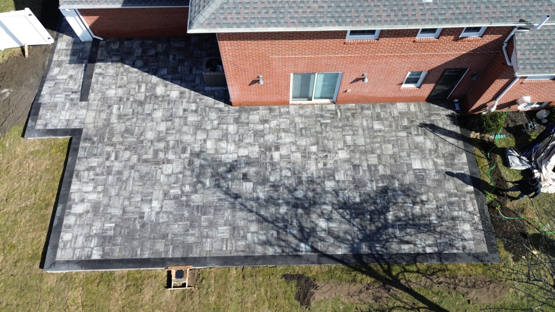 Finished paver patio installation with decorative border at a home in Livingston, Essex County, New Jersey.