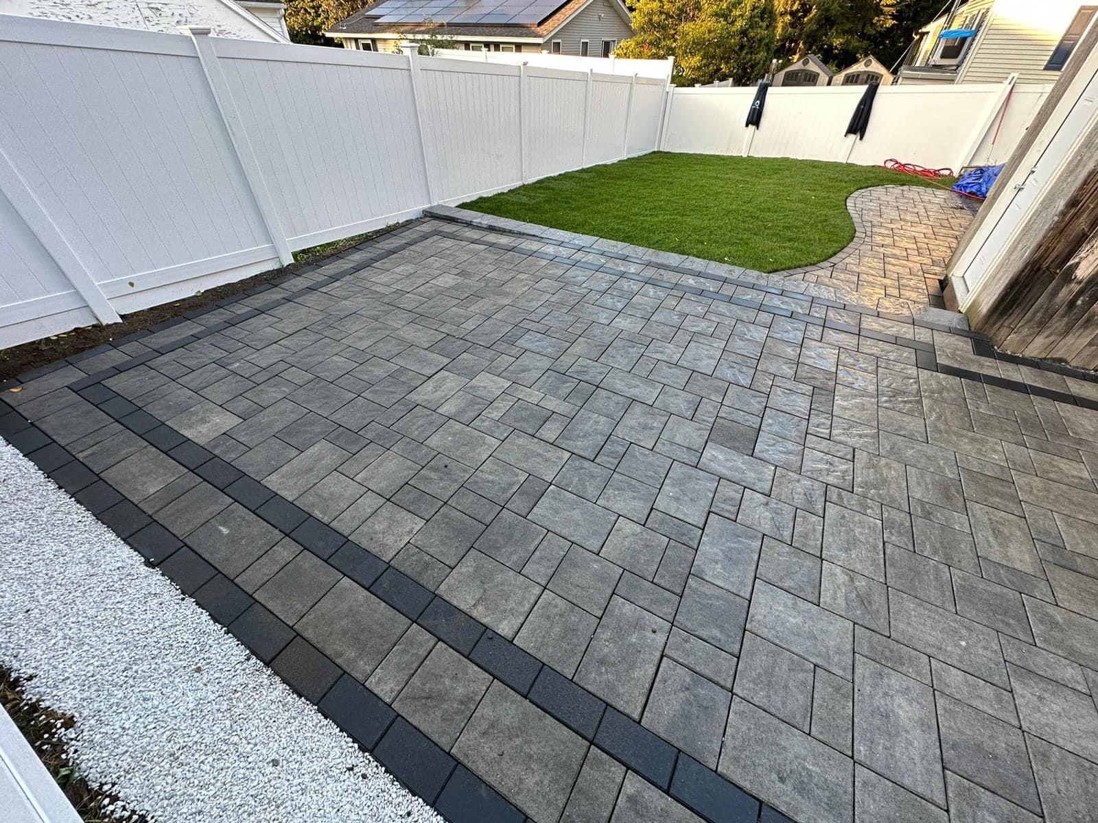 Newly installed patio pavers with green grass in Emerson, Bergen County, NJ, ready for patio waterproofing by Masonry Pro.