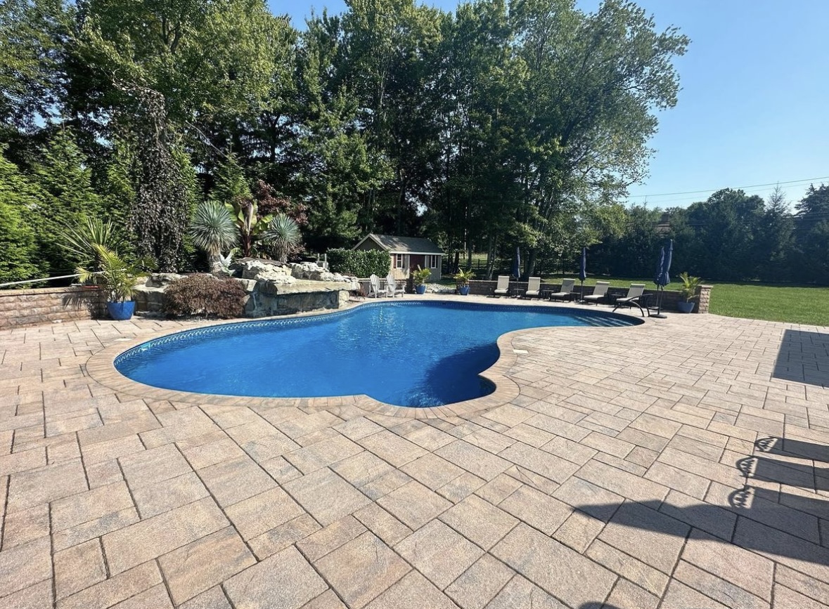 Finished paver patio surrounding an inground pool at a home in Kinnelon, Morris County, New Jersey by Masonry Pro Construction.