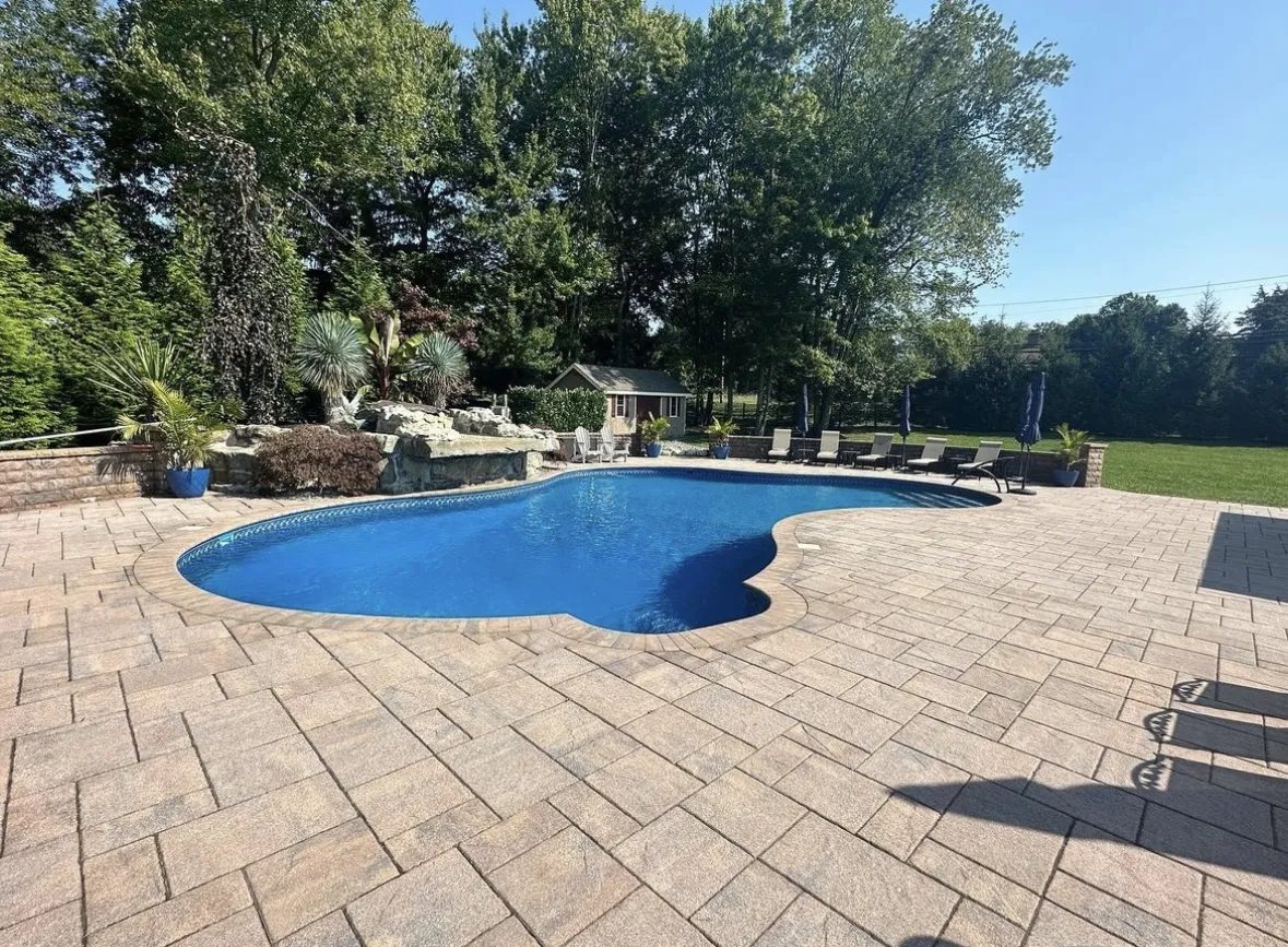 Finished paver patio surrounding an inground pool at a home in Kinnelon, Morris County, New Jersey by Masonry Pro Construction.