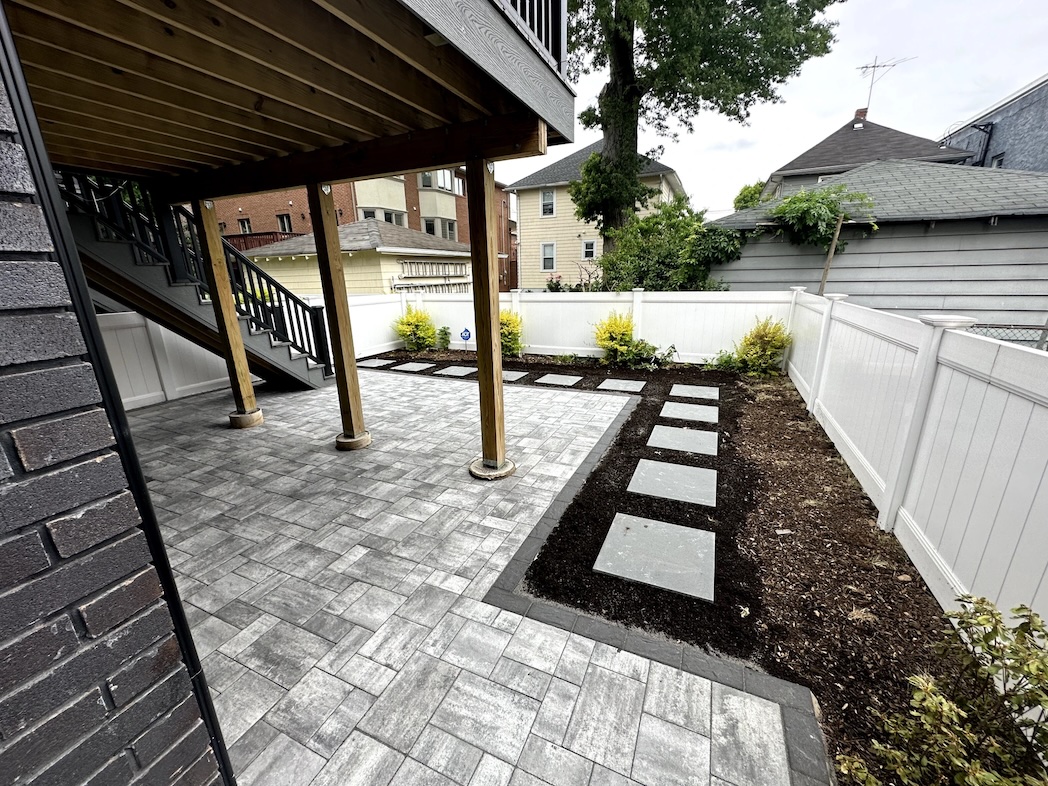 Paver patio and stepping stone walkway installation under a deck at a residential property in Palisades Park, Bergen County, NJ, by Masonry Pro Construction.