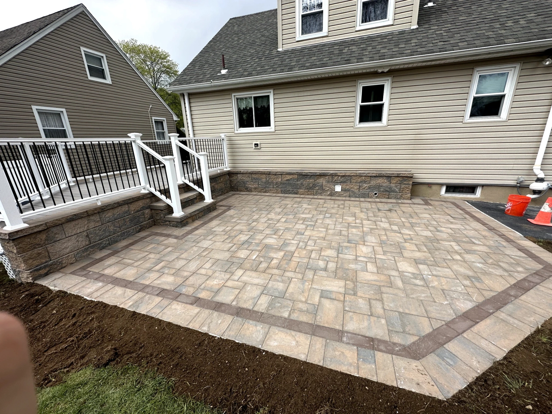 Paver patio installation with stone veneer retaining wall at a residential property in Pompton Lakes, Passaic County, NJ, by Masonry Pro Construction.