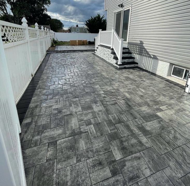 Dark paver patio installation with stone steps at a residential property in Ridgewood, Bergen County, NJ, by Masonry Pro Construction.