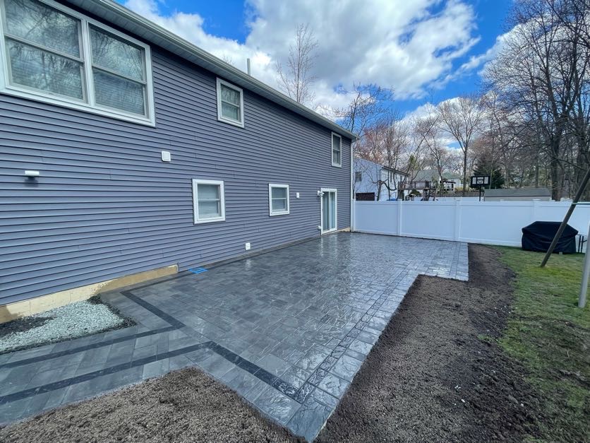 Newly installed paver patio next to a gray house in Westwood, Bergen County, New Jersey