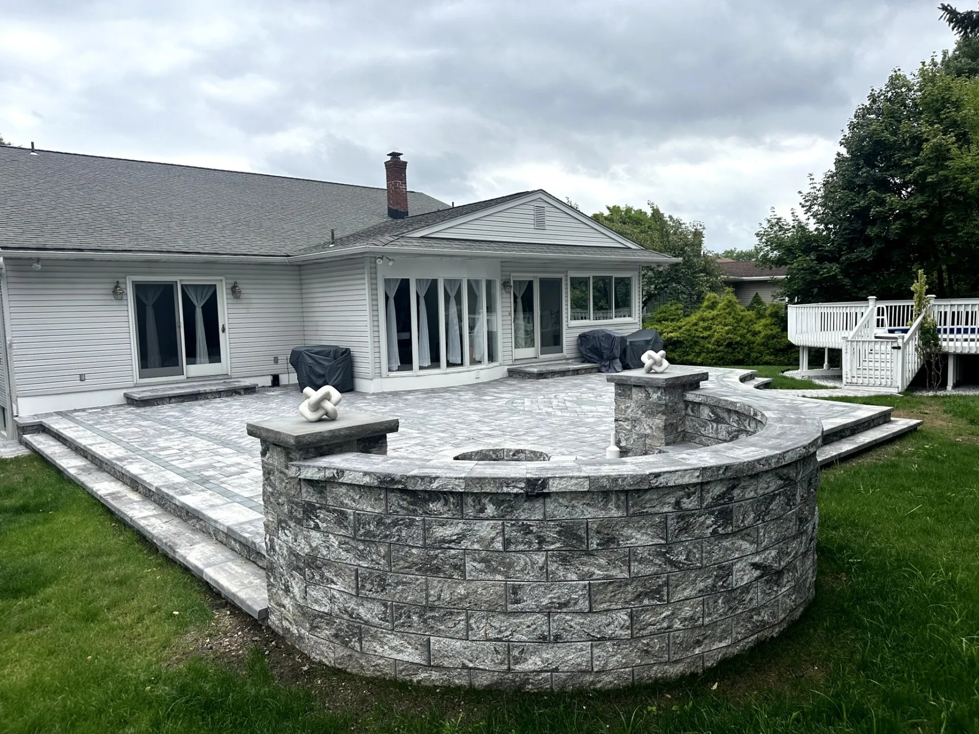 Paver patio with a curved masonry wall and fire pit in Clifton, Passaic County, NJ by Masonry Pro Construction