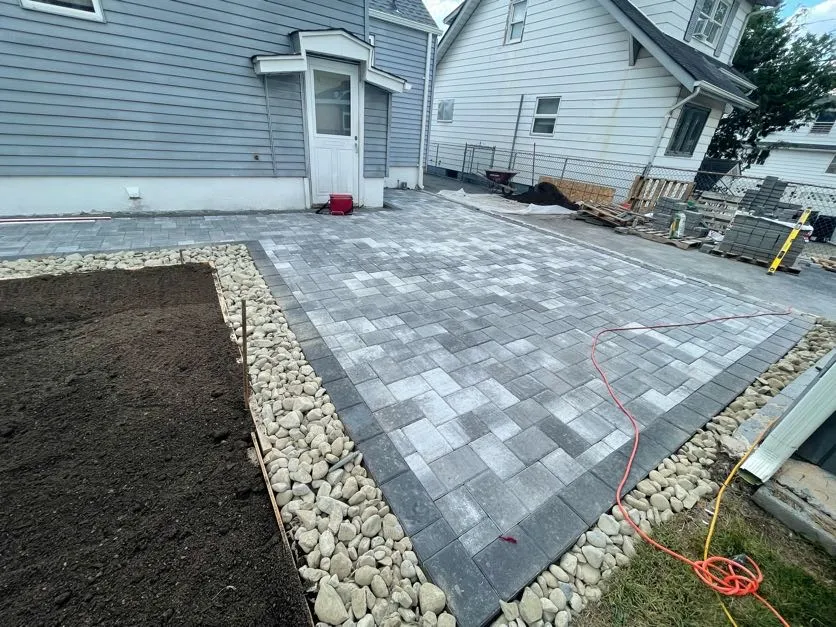 Finished paver patio with decorative rock border and garden bed, ready for use in Paterson, Passaic County, New Jersey