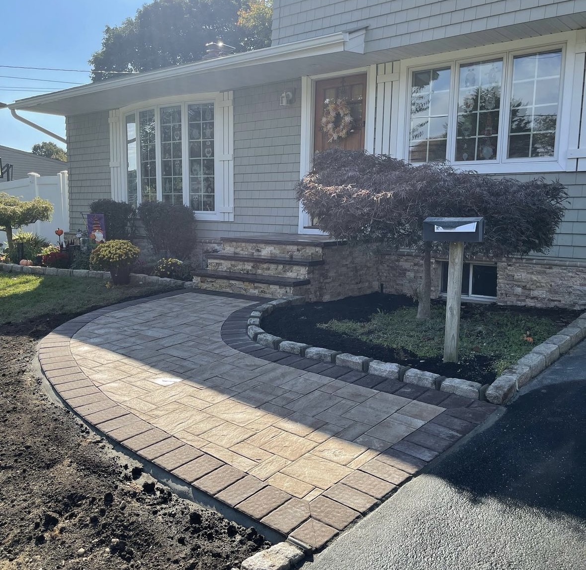 Curved paver walkway and stone veneer steps leading to the front entrance of a home in Rutherford, Bergen County, NJ, by Masonry Pro Construction.