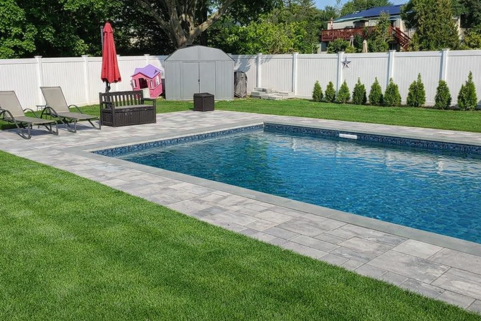 Paver patio installation around a backyard pool with landscaping in Ridgewood, Bergen County, NJ, by Masonry Pro Construction.