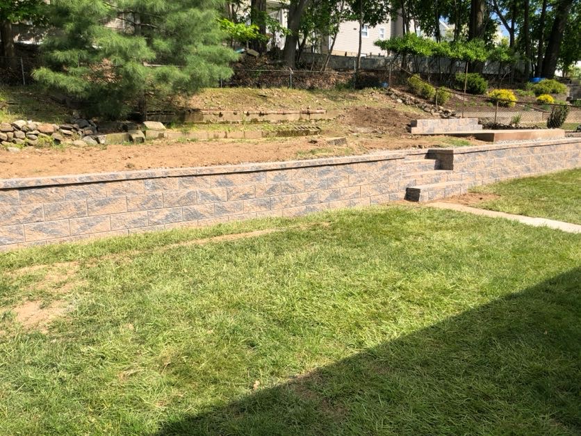 Retaining wall construction at a residential property in Totowa, Passaic County, NJ by Masonry Pro Construction.