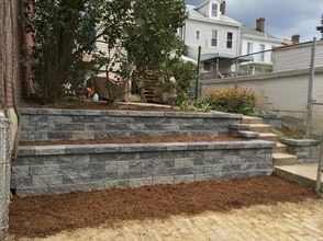 Multi-level stone retaining wall with steps built in a residential backyard in Hackensack, Bergen County, NJ, by Masonry Pro Construction.