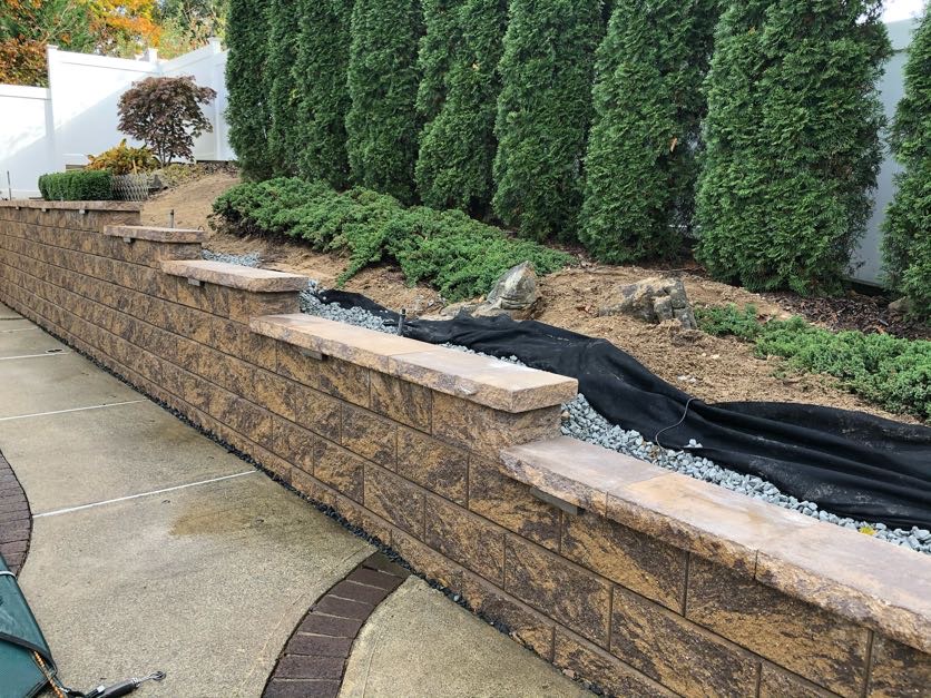 Finished retaining wall and landscape grading along a paved walkway in Wayne, Passaic County, New Jersey