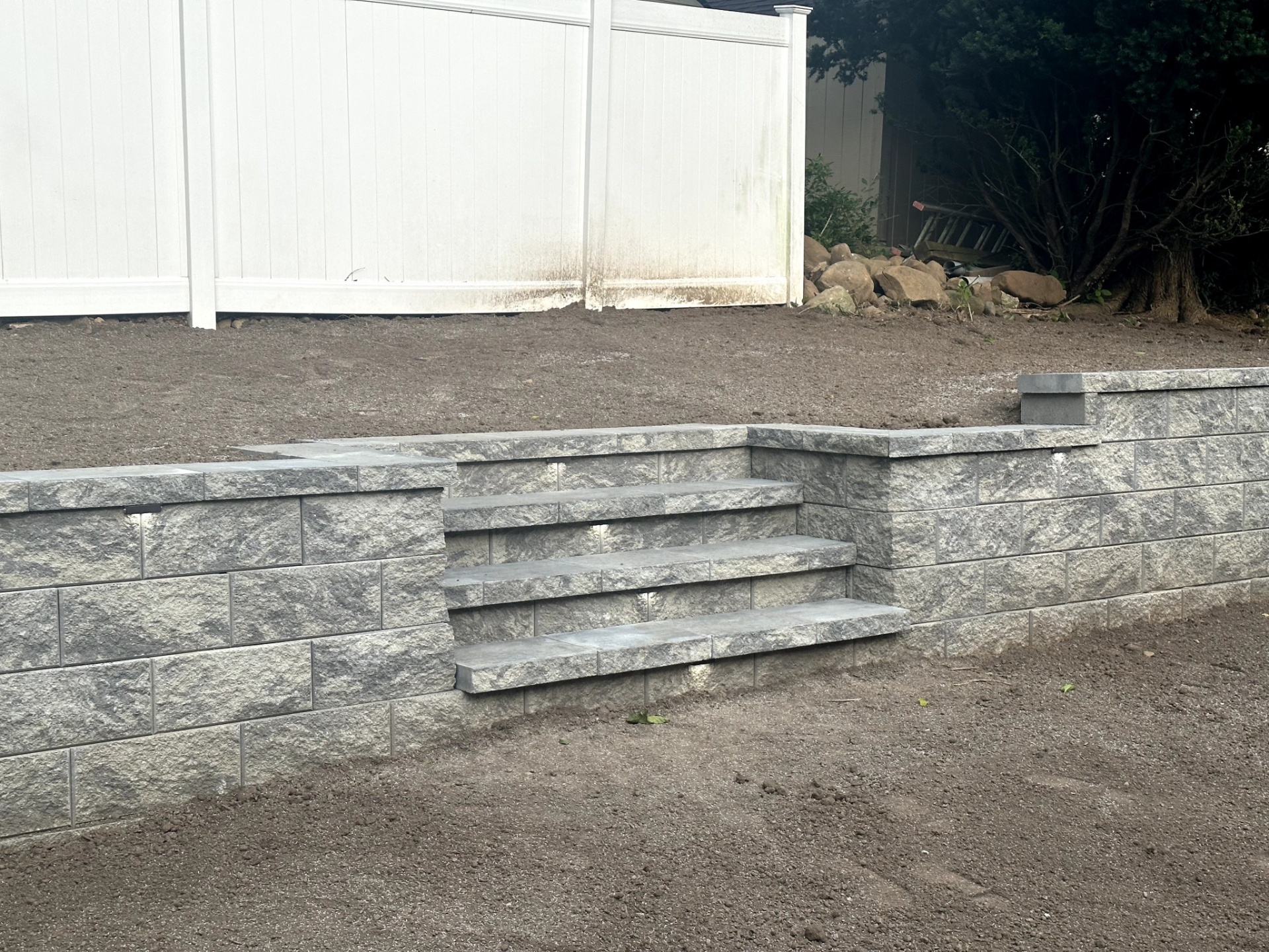 Retaining wall with integrated steps in a backyard in Wayne, Passaic County, NJ by Masonry Pro Construction