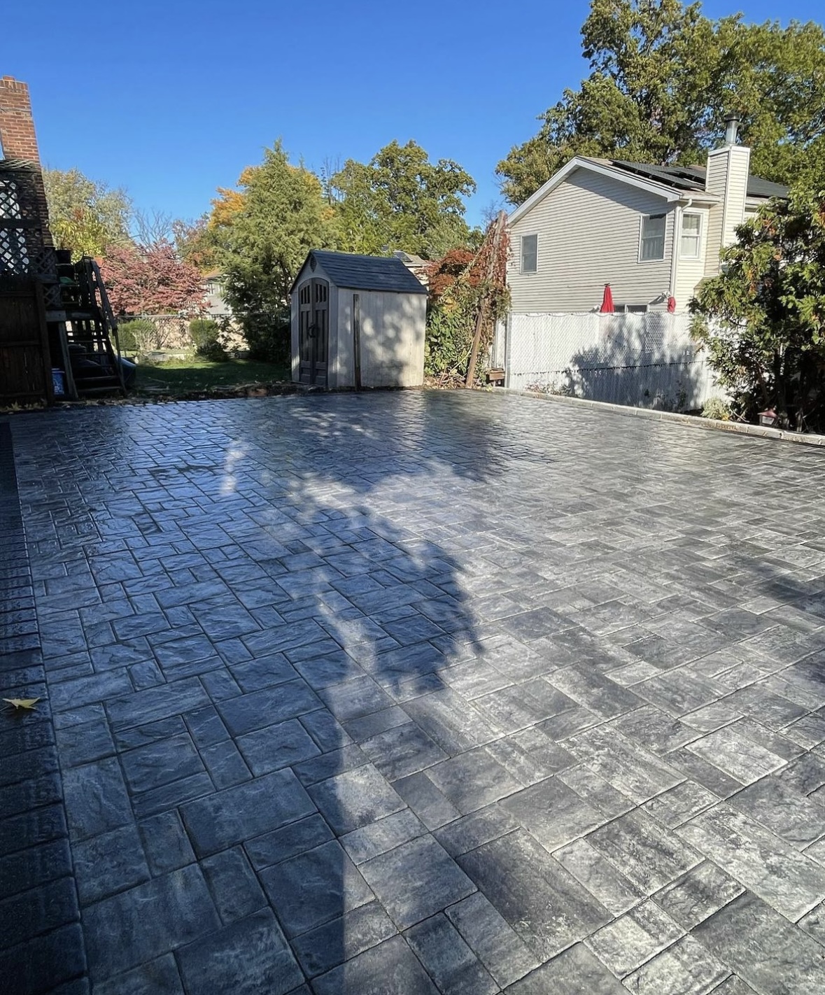 Large stone paver patio installation in a backyard in Little Falls, Passaic County, NJ, by Masonry Pro Construction.