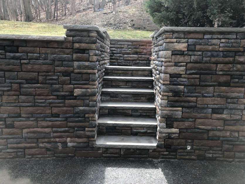 Finished stone retaining wall with integrated stone steps at a hillside property in Franklin Lakes, Bergen County, New Jersey.