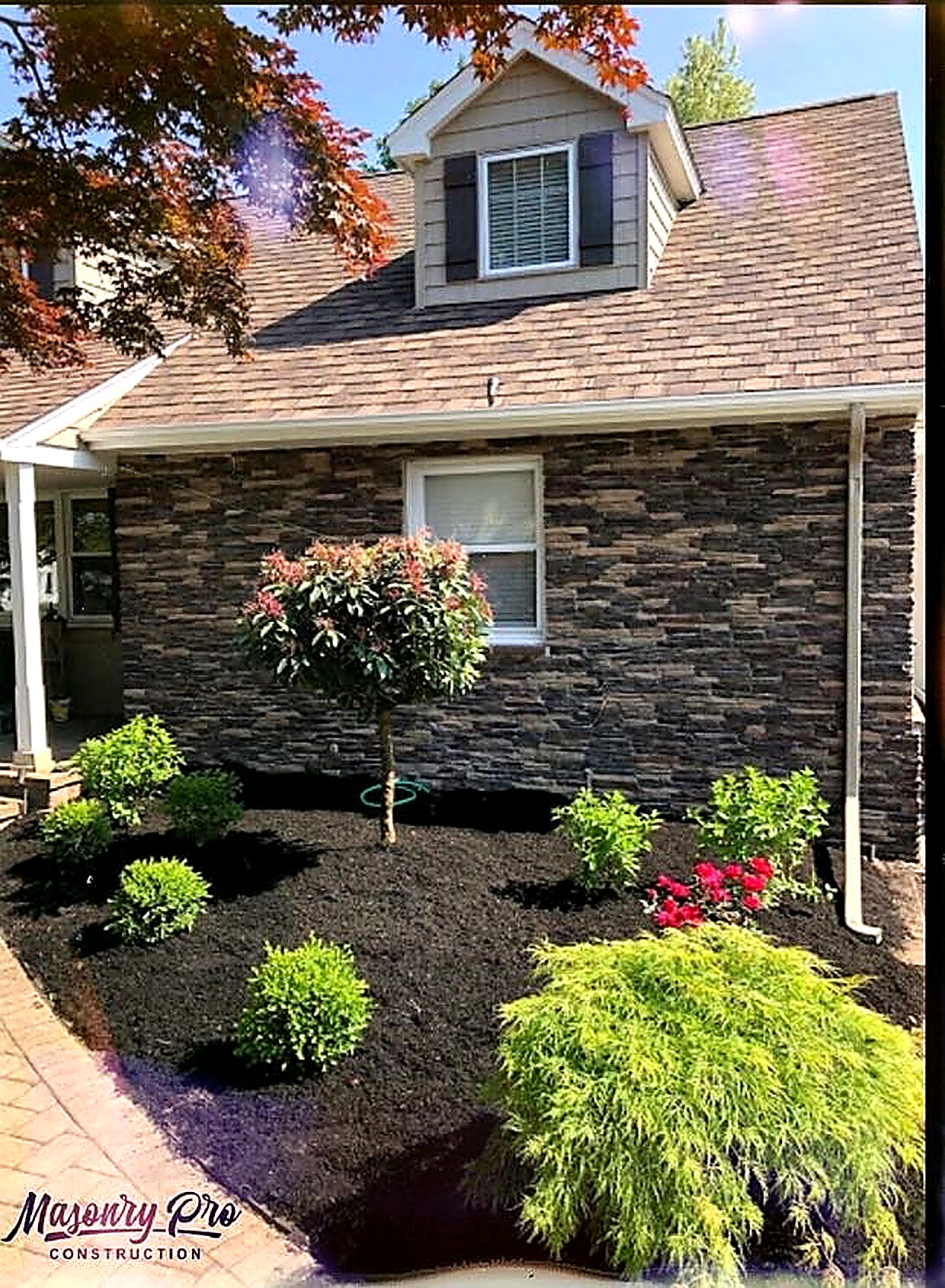 Stone veneer siding installation on a residential home with landscaping in Passaic, Passaic County, NJ, by Masonry Pro Construction.